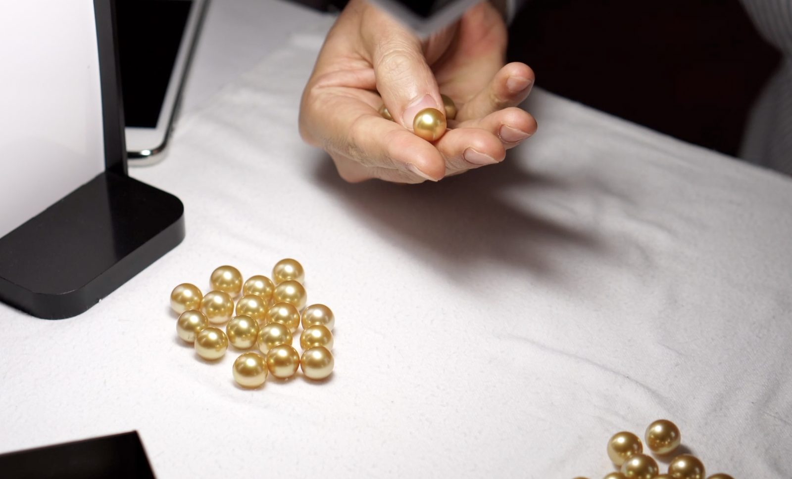 A golden South Sea pearl examined under the lamp before an auction