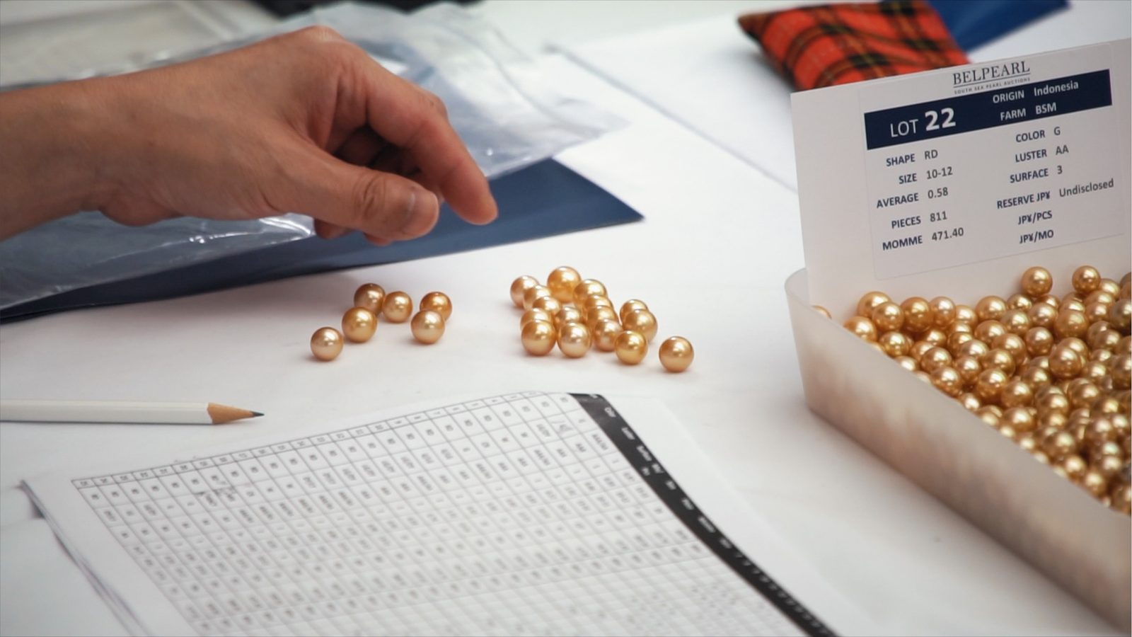 A lot of golden South Sea pearls with its lot number on the viewing table